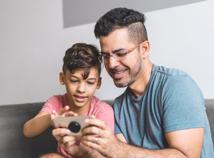 Mother shows her daughter a phone, using screens together can help with tantrums